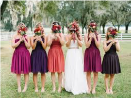 Bride and Bride's Maids all standing next to each other holding flowers covering their faces