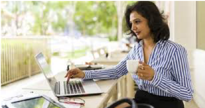 Woman drinking coffee and working on laptop